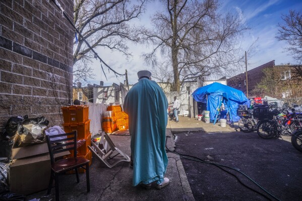 Imam Omar Niass, right, checks his phone as he enters the backyard of Bronx's Masjid Ansaru-Deen mosque, Friday, March 15, 2024, in New York. (AP Photo/Bebeto Matthews)